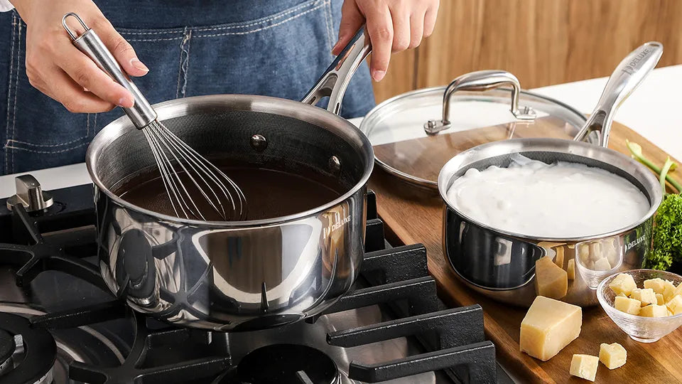 Whisking chocolate sauce in Deluxe Cookware stainless steel saucepan on gas stove beside cream pot, cheese and broccoli